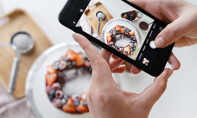woman hand taking photo on smartphone of delicious decorated cake