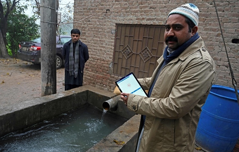 In this picture taken on January 7, 2022, Aamer Hayat Bhandara , co-founder of Digital Dera, gives interviews to AFP while showing how to close a water pump through his digital app in Chak Twenty-six SP.