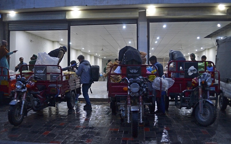 In this picture taken on January 8, 2022, workers of Taza Transforming Agriculture load vegetable bags on rickshaws at a distributing point in Lahore.  — AFP